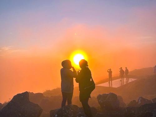 people standing on top of a mountain at sunset at Guesthouse HOALOHA 4 SEASONS in Chino