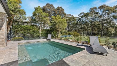 an image of a swimming pool in a yard with two chairs at Que Syrah in Pokolbin