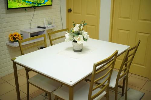 a white table with a vase of flowers on it at Fabulous Condo Suite One Spatial Tower2 in Iloilo City