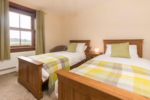 a bedroom with two beds and a window at Stanley Lodge Farmhouse in Cockerham