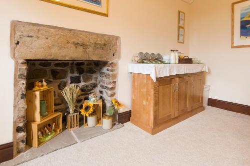a living room with a stone fireplace and a sink at Stanley Lodge Farmhouse in Cockerham