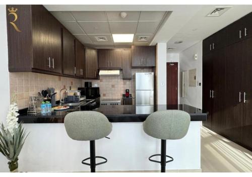 a kitchen with two chairs and a counter top at Stylish Hydra Studio -Serene City Escape in Abu Dhabi
