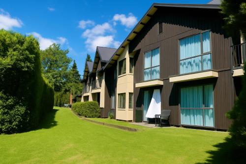 a building with a green lawn in front of it at Village Lake Luxury Apartments in Hanmer Springs