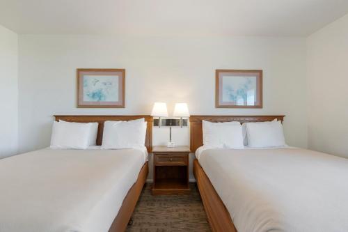 two beds in a hotel room with white sheets at Crescent Beach Motel in Crescent City