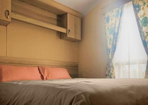 a bedroom with a bed and a window at Towervans Caravan Park in Mablethorpe