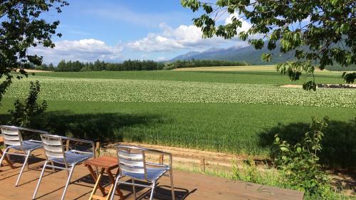 four chairs and a table in front of a field of flowers at Akane-yado in Nakafurano