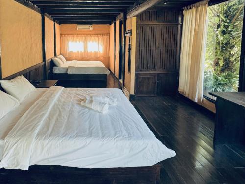 a bedroom with a large white bed and a window at Cọ Retreat Da Bac in Hòa Bình