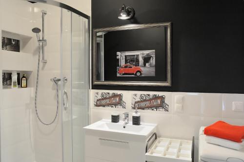 een badkamer met een douche, een witte wastafel en een spiegel bij Apartament Kabaty in Warschau