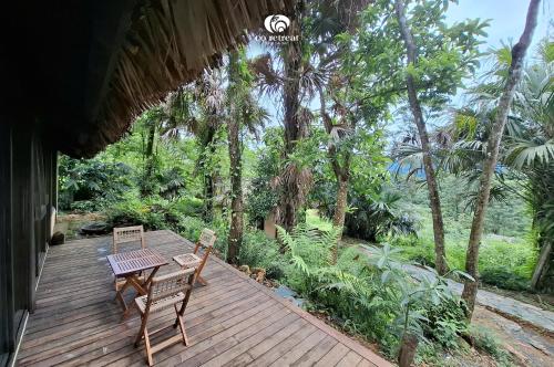 a wooden deck with two chairs and a table at Cọ Retreat Da Bac in Hòa Bình