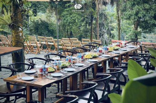 a long wooden table with chairs and food on it at Cọ Retreat Da Bac in Hòa Bình