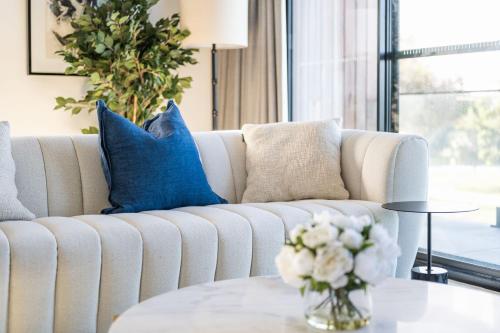 a living room with a white couch with blue pillows at Surf House Cape - Cape Paterson in Cape Paterson