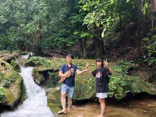 two people holding up peace signs in front of a stream at Cọ Retreat Da Bac in Hòa Bình