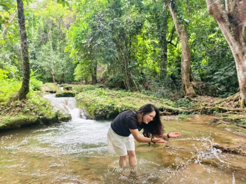 a woman standing in the water in a creek at Cọ Retreat Da Bac in Hòa Bình