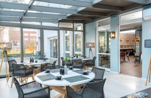 a restaurant with tables and chairs and windows at Leonardo Boutique Hotel Berlin City South in Berlin
