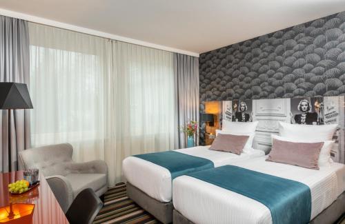 a hotel room with two beds and a chair at Leonardo Boutique Hotel Berlin City South in Berlin