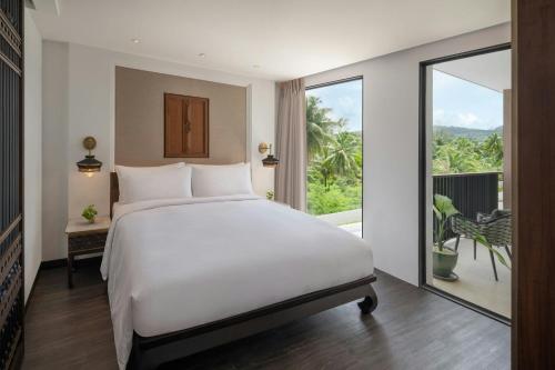 a bedroom with a white bed and a large window at Marriott Vacation Club, Khao Lak Beach Resort in Khao Lak