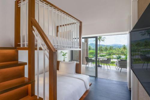 a bedroom with a bed and a balcony with a table at Marriott Vacation Club, Khao Lak Beach Resort in Khao Lak