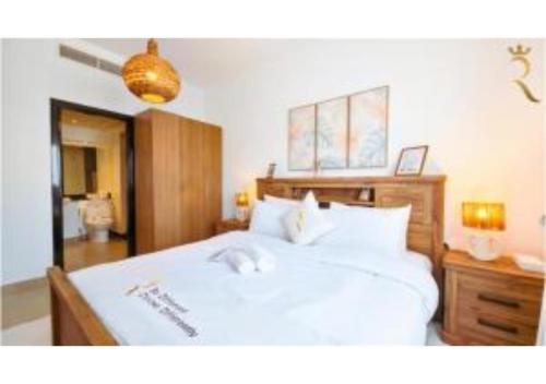 a bedroom with a white bed with a wooden headboard at Reef Edge 1BR - Elegant Coastal Getaway in Abu Dhabi