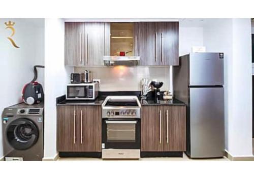 a kitchen with a refrigerator and a stove at Reef Edge 1BR - Elegant Coastal Getaway in Abu Dhabi