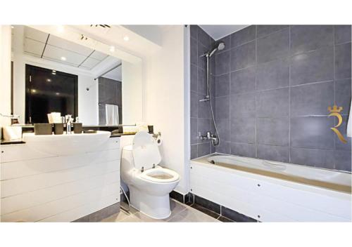 a bathroom with a toilet and a tub and a sink at Reef Edge 1BR - Elegant Coastal Getaway in Abu Dhabi