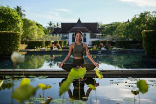 a woman sitting in a yoga pose in front of a pond at Marriott Vacation Club, Khao Lak Beach Resort in Khao Lak