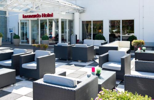 a patio with chairs and tables in front of a building at Leonardo Hotel Heidelberg in Heidelberg