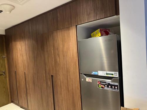 einem Kühlschrank aus Edelstahl neben einem Holzschrank in der Unterkunft استوديو فاخر مفروش في الشارقة الزاهية in Sabkhah