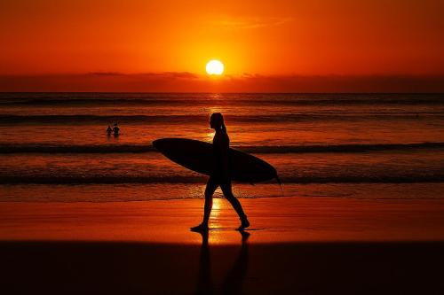 a person walking on the beach with a surfboard at Mana Suites Bali in Kuta