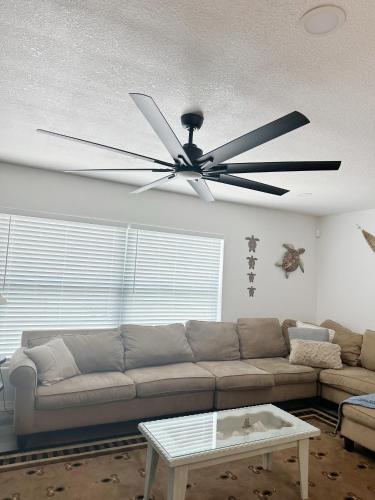 a living room with a couch and a ceiling fan at Spacious Clearwater Vacation House with Cowboy Pool Pet Friendly Fire Pit Life size Games Close to Clearwater Beach Biking Trail Farmers Markets S Harbor Health Spa Baycare Ballpark and Ruth Eckerd Hall Golf Courses in Clearwater
