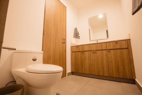 a bathroom with a white toilet and a wooden cabinet at Indico in Mérida