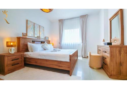 a bedroom with a large bed and a dresser at Elegant 1BR - Al Reef Urban Haven in Abu Dhabi