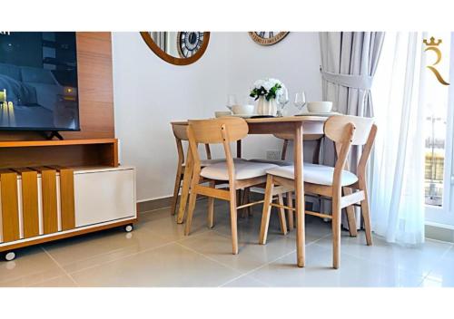 a dining room table with chairs and a television at Elegant 1BR - Al Reef Urban Haven in Abu Dhabi