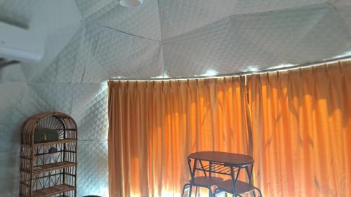a table and two chairs in front of an orange curtain at Dream Estate Resort in Senggigi 