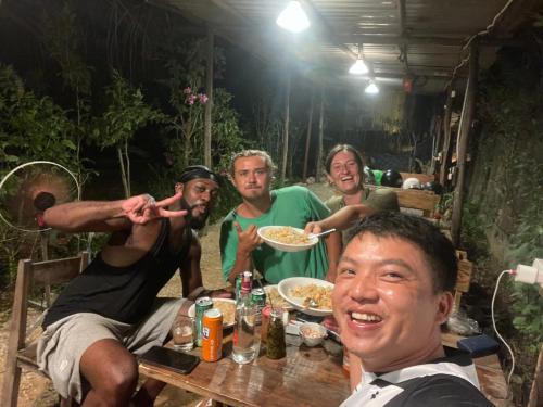 a group of men sitting around a table eating food at Vuglamping in Hue