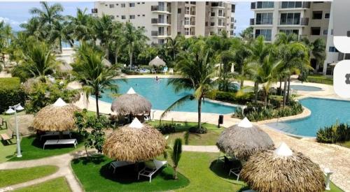 a resort with a swimming pool with straw umbrellas at Beautiful Beach in El Quindio