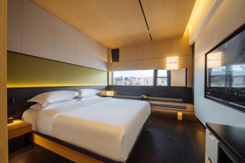 a large white bed in a room with a window at SFEEL设计师酒店 Designer Hotel 昆明穿金路地铁站店 in Kunming