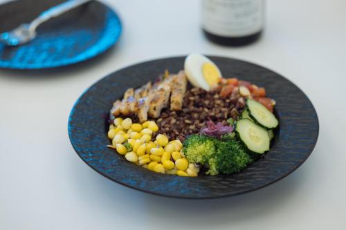 a black plate of food with beans and vegetables at SFEEL设计师酒店 Designer Hotel 昆明穿金路地铁站店 in Kunming
