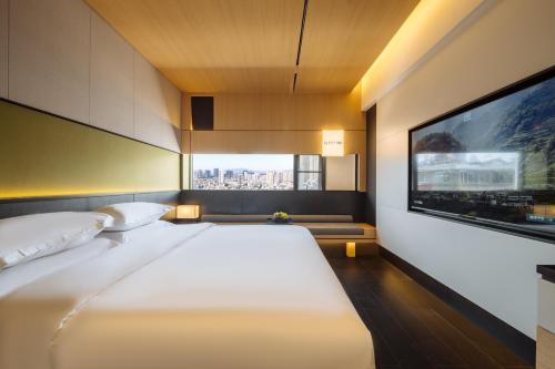 a bedroom with a large bed and a tv at SFEEL设计师酒店 Designer Hotel 昆明穿金路地铁站店 in Kunming