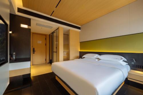 a bedroom with a large white bed in a room at SFEEL设计师酒店 Designer Hotel 昆明穿金路地铁站店 in Kunming