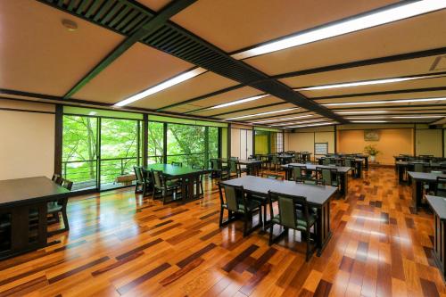 a dining room with tables and chairs and windows at Momijiya Honkan Takaosansou in Kyoto