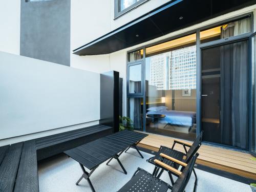 a balcony with two chairs and a bench and a bedroom at SFEEL设计师酒店 Designer Hotel 昆明穿金路地铁站店 in Kunming