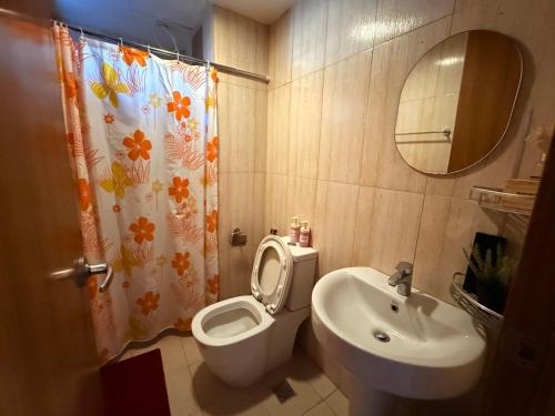 a bathroom with a toilet and a sink and a mirror at 1 Bedroom Bayview Condo near SLMEC & US Embassy in Manila