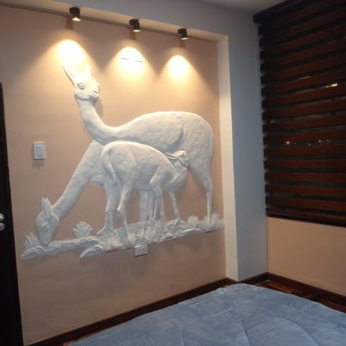 a sculpture of a llama and a baby giraffe on a wall at hermoso,tematico y espacioso departamento in Allpacoma