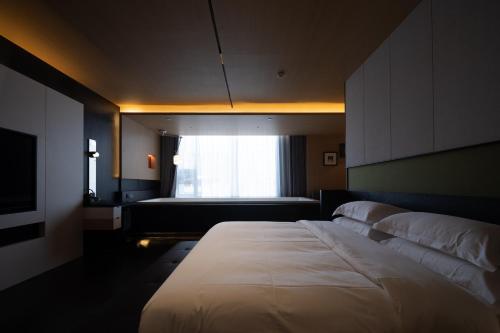 a bedroom with a large bed and a window at SFEEL设计师酒店 Designer Hotel 昆明穿金路地铁站店 in Kunming