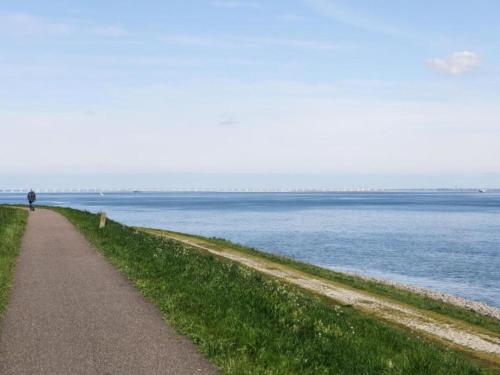 a person walking along a path next to the water at Cozy Seaside Retreat in Zeeland in Wemeldinge