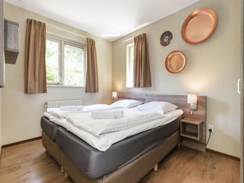 a large bed in a bedroom with two windows at Brabant Holiday Home With Sauna 