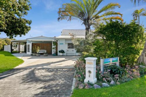 a house with a palm tree and a garden at Funky Lil Shack - by the jetty in Bongaree