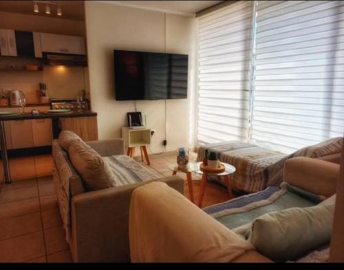 a living room with two couches and a flat screen tv at Hermoso Alojamiento Cerca de todo en La Serena in La Serena