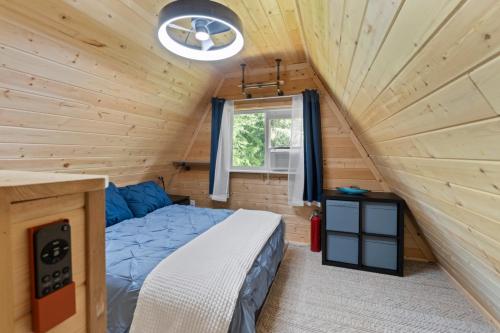 a bedroom in a log cabin with a bed and a window at A-Frame At Entrance to Rainier- Hot Tub & WiFi in Ashford