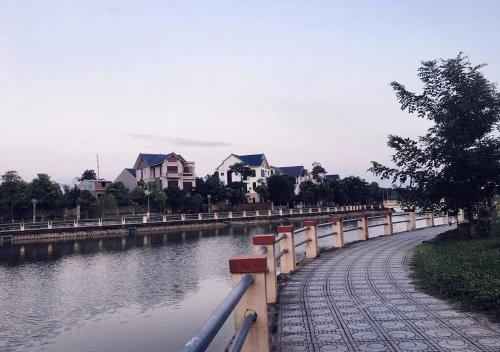 a walk way next to a river with houses at Nha Nghi Phu Quy in Phú Nặng